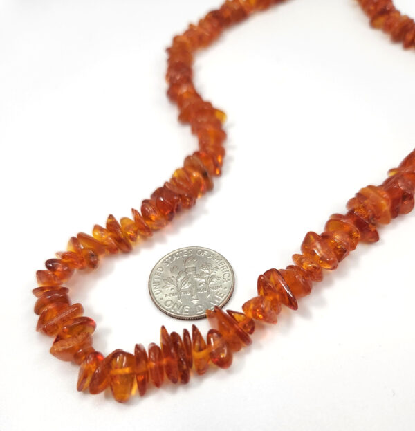 close-up of Baltic amber necklace with dime to help show scale