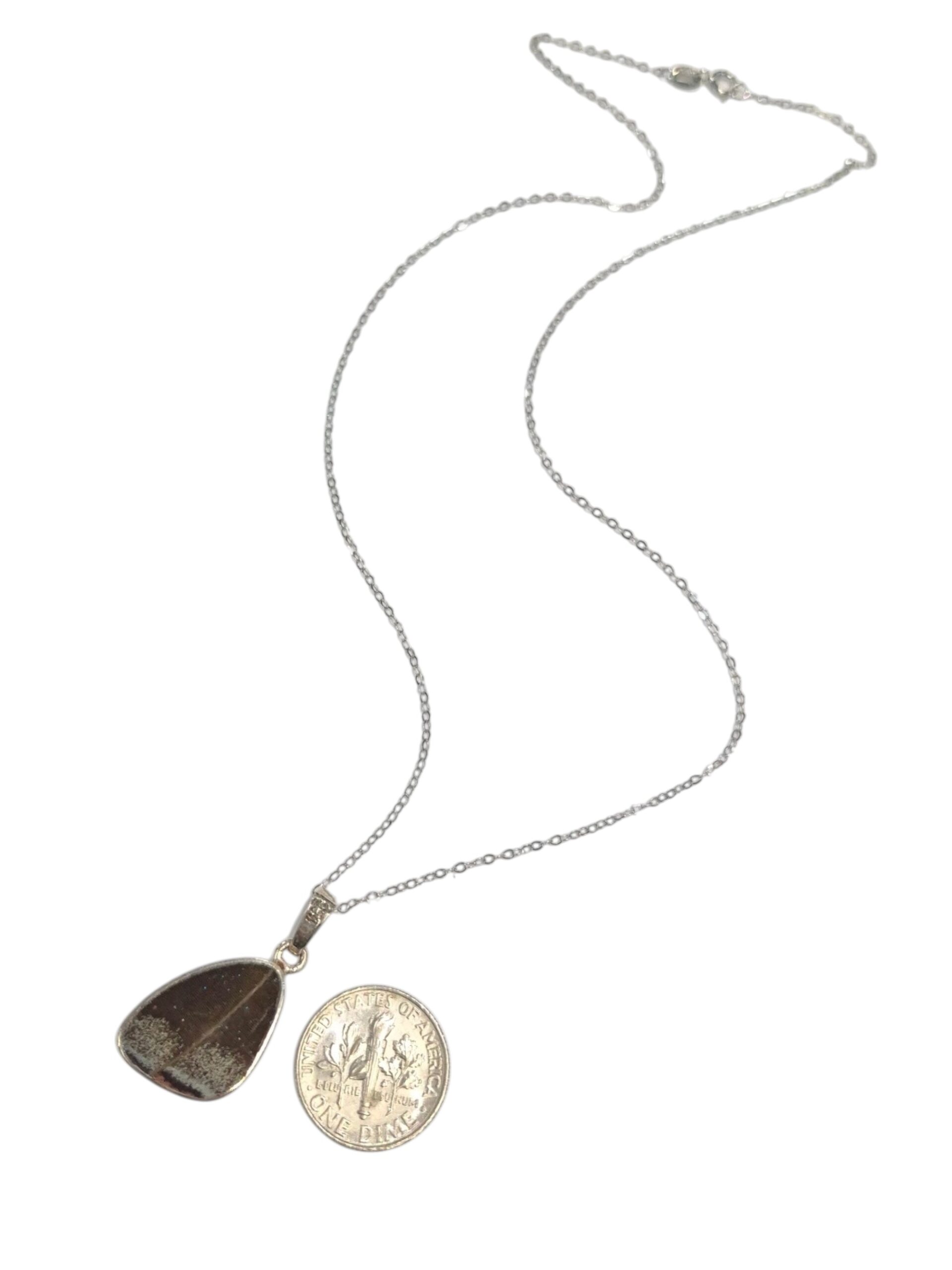 backside of real blue morpho butterfly wing necklace with dime for size comparison, no butterflies are harmed