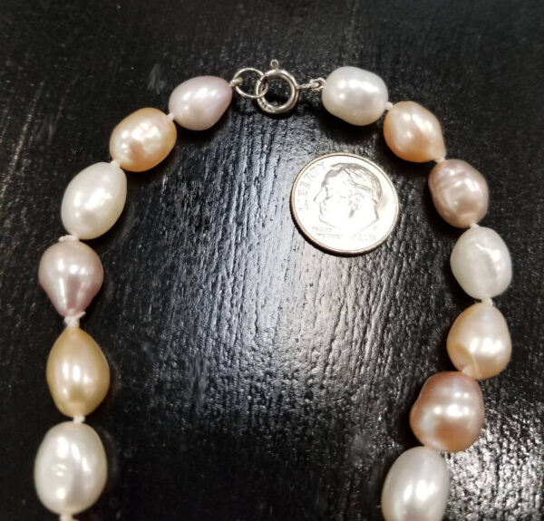 close up of baroque shape fresh water pearl necklace with dime for clasp