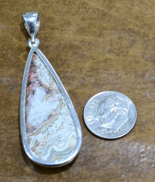 back of handmade crazy lace agate drop pendant with dime for size