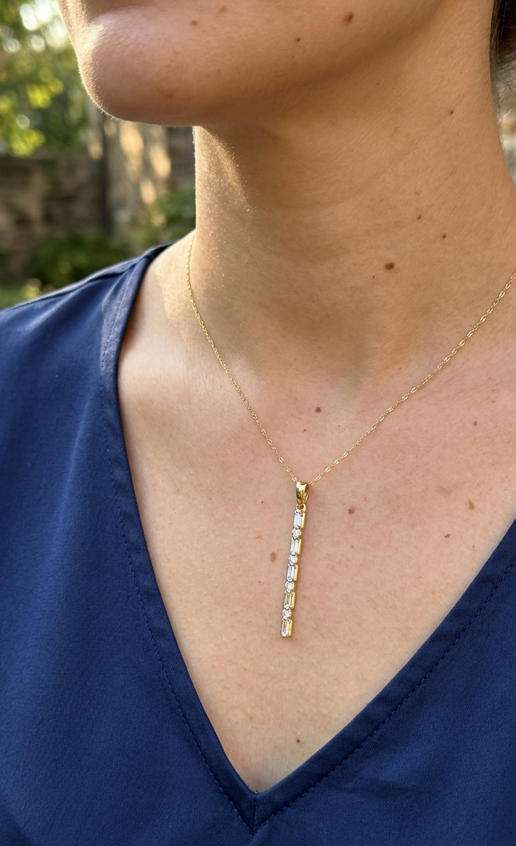 long diamond pendant on thin gold chain necklace on woman
