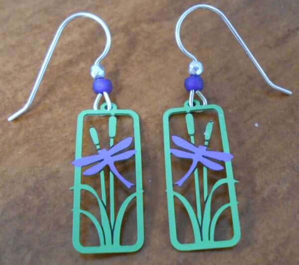 These dragonfly earrings are handmade by Sienna Sky and feature a dragonfly in front of a cattail plant.
