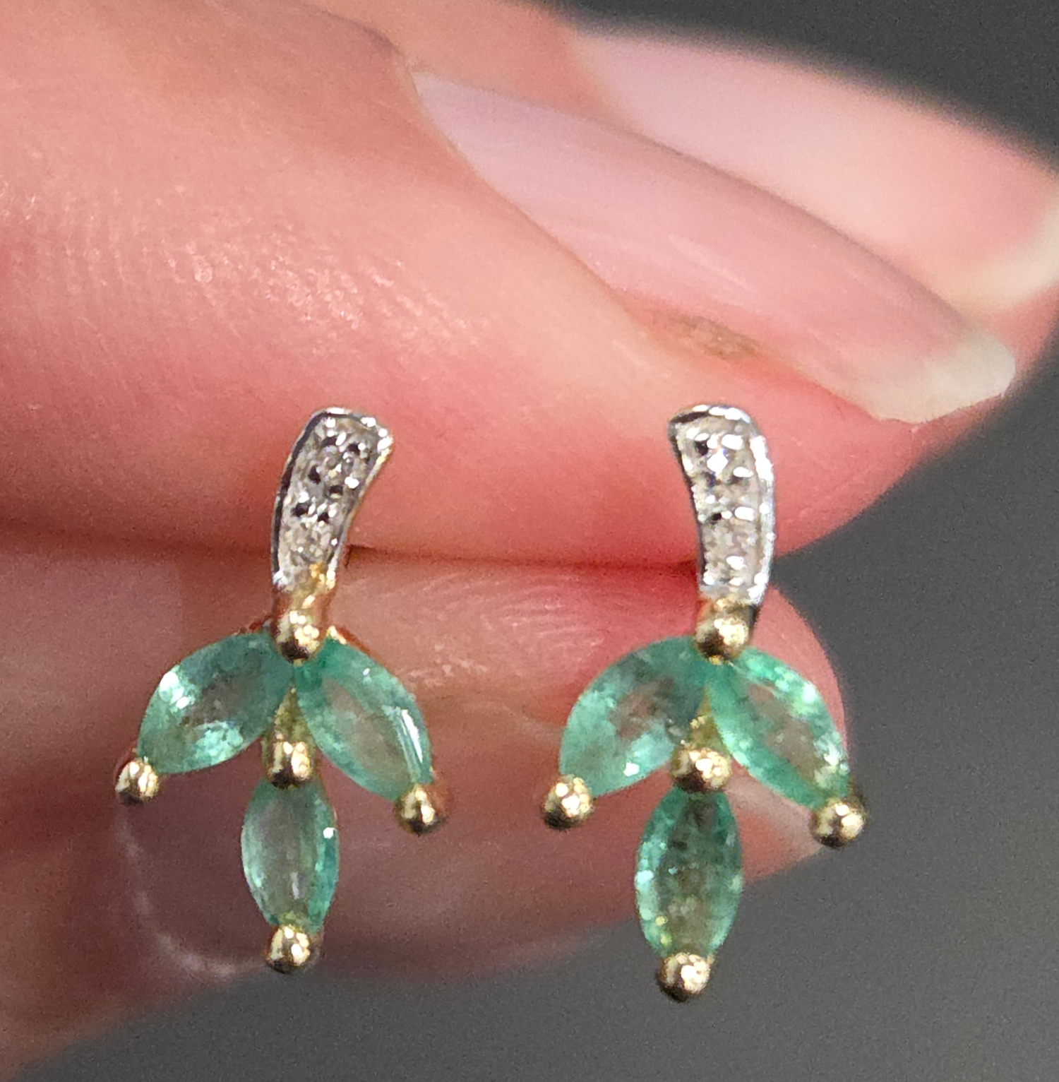 diamond and emerald leaf earrings in hand