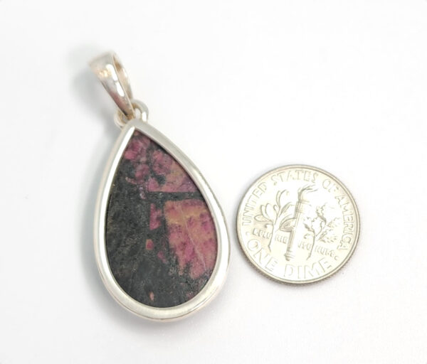 backside of eudialyte pendant with dime for size comparison