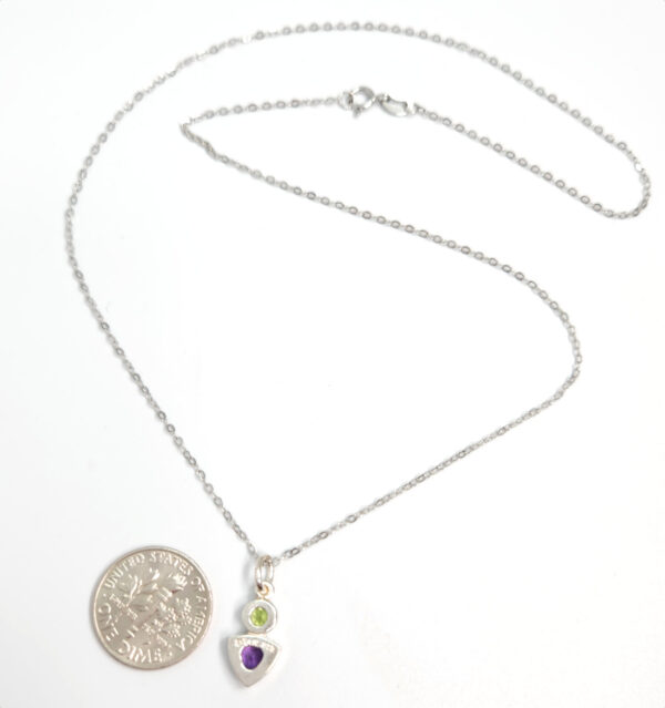 backside of peridot and amethyst pendant with dime for size comparison