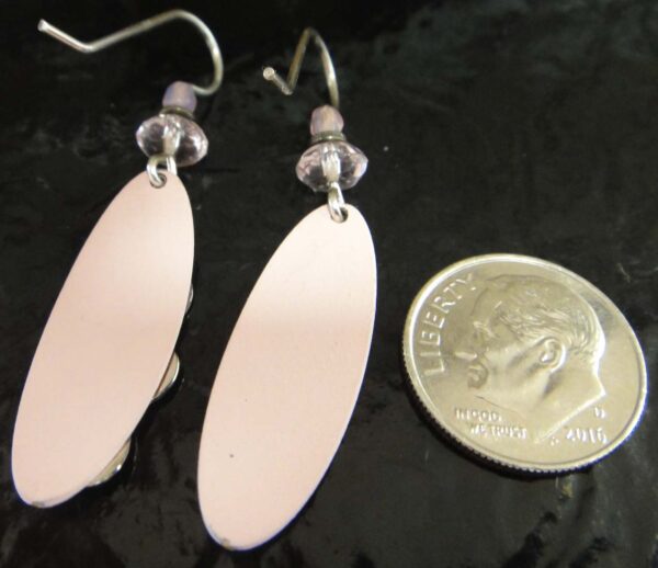 Back of pink dangle earrings with dime for scale