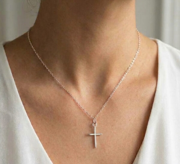 dainty cross necklace on model's neck