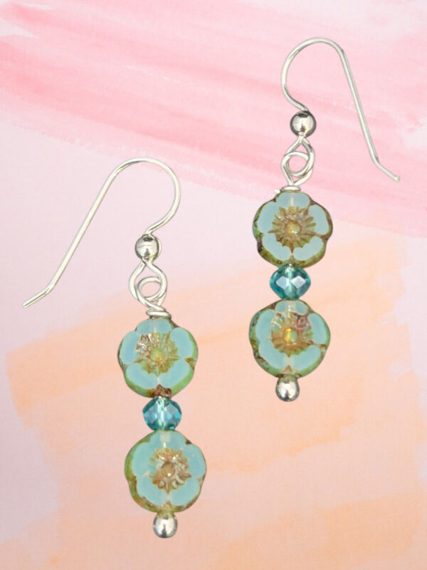 teal tropical flower earrings on pastel background